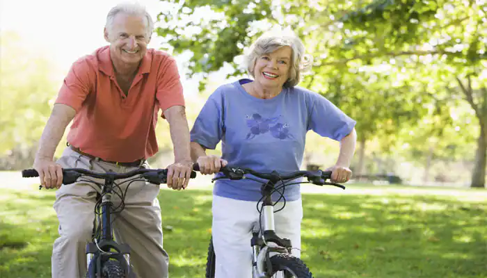 Older man and woman riding bikes in a park