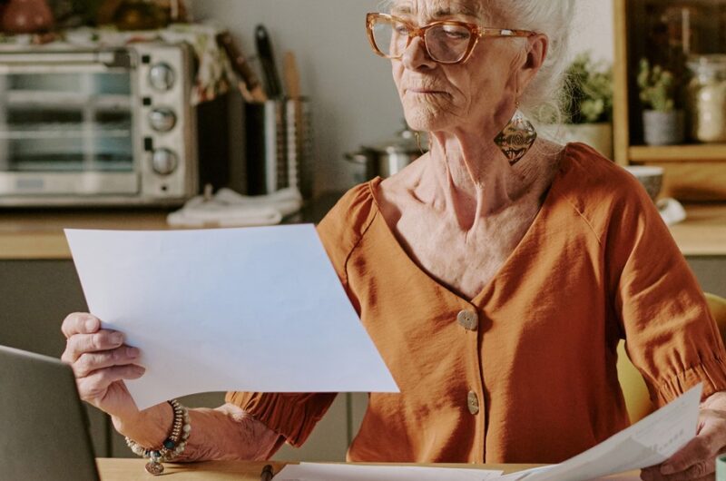 Older woman reivewing paperwork at computer
