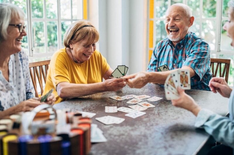 Group of older adult roommates playing cards.