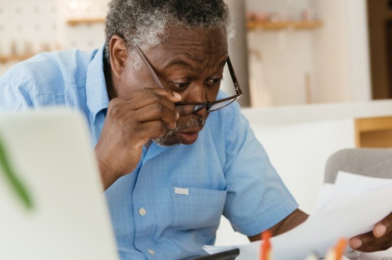 older adult looking surprised at his bill